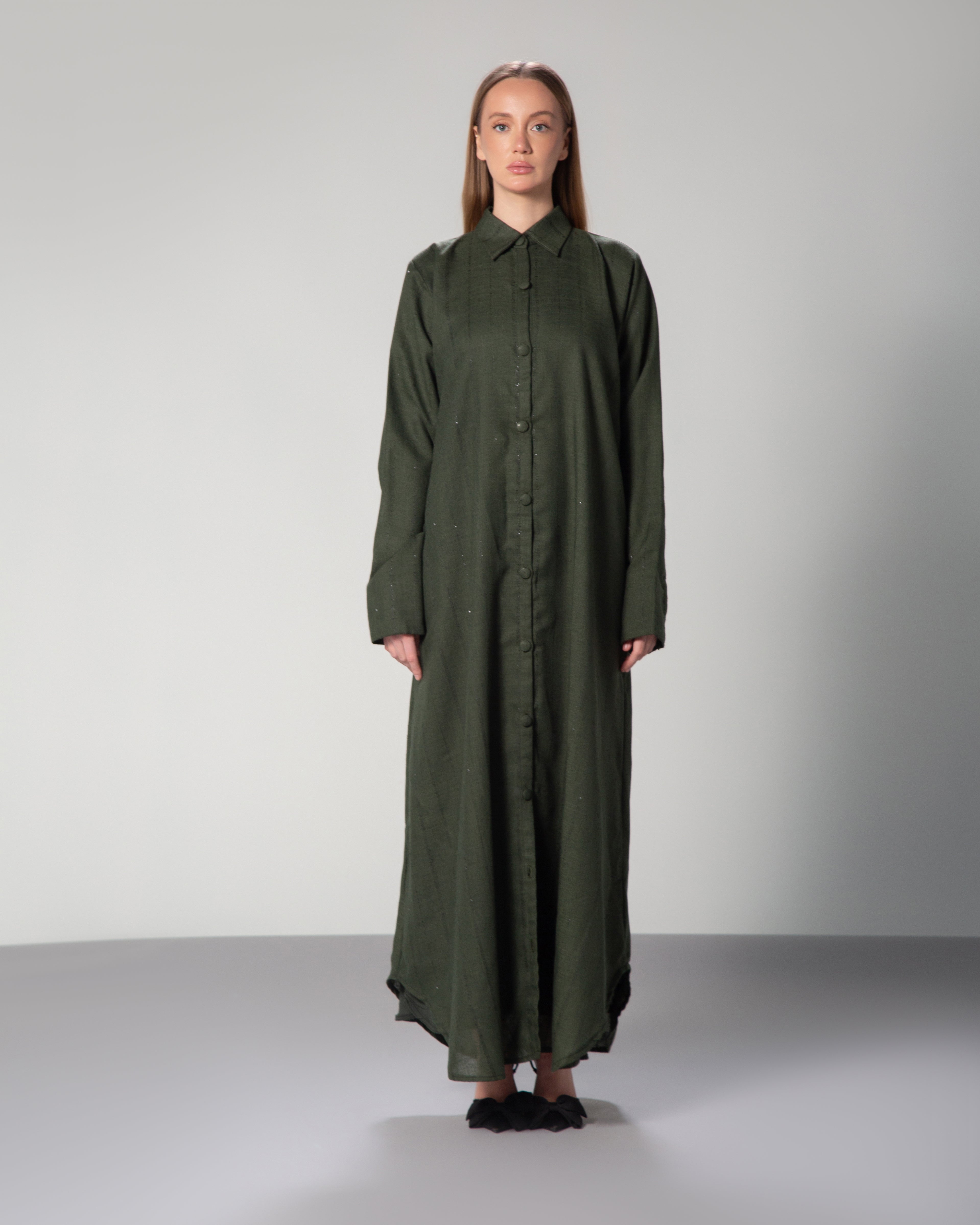A woman wearing a green linen collared abaya with sequins and fabric-covered buttons middle east saudi kuwait qatar modest fashion 