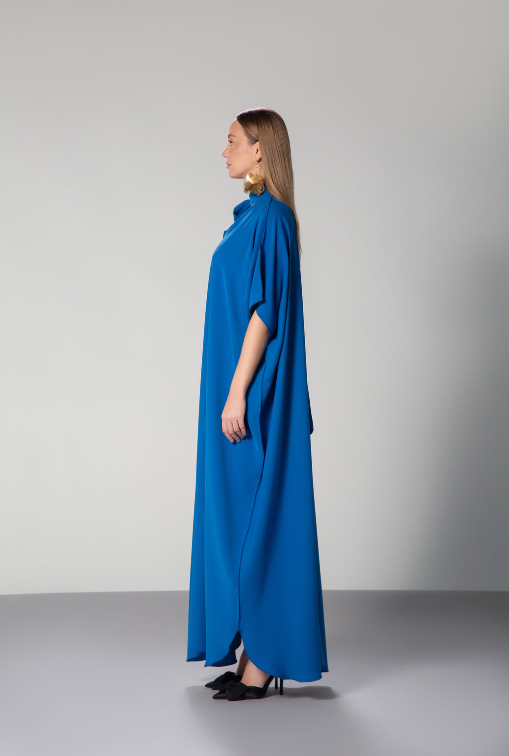 Female model wearing  blue dress with short sleeves and high collar by Omni The Label side profile studio shot ideal for UAE KSA Qatar modest fashion lovers KSA UAE Qatar
