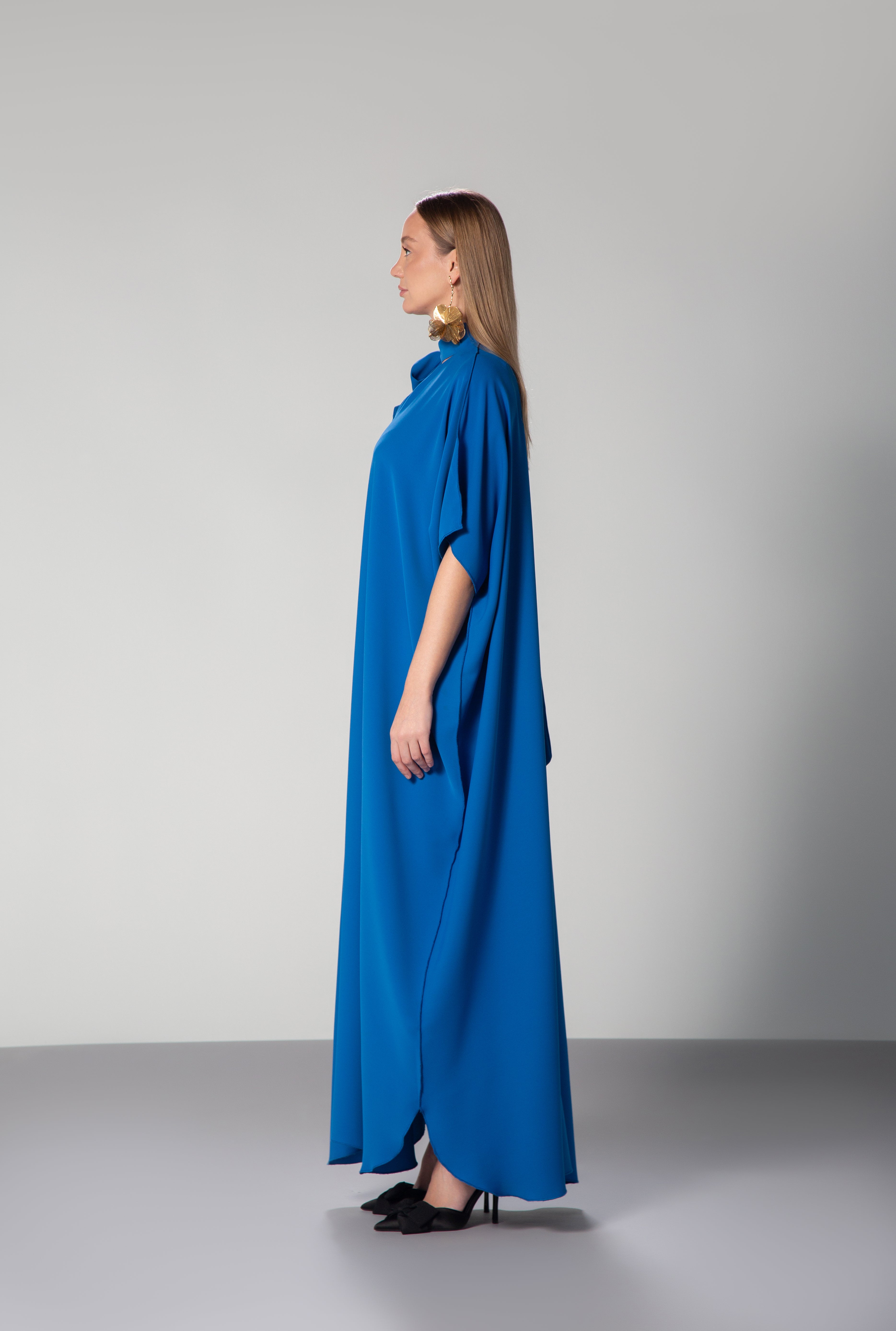 Female model wearing  blue dress with short sleeves and high collar by Omni The Label side profile studio shot ideal for UAE KSA Qatar modest fashion lovers KSA UAE Qatar
