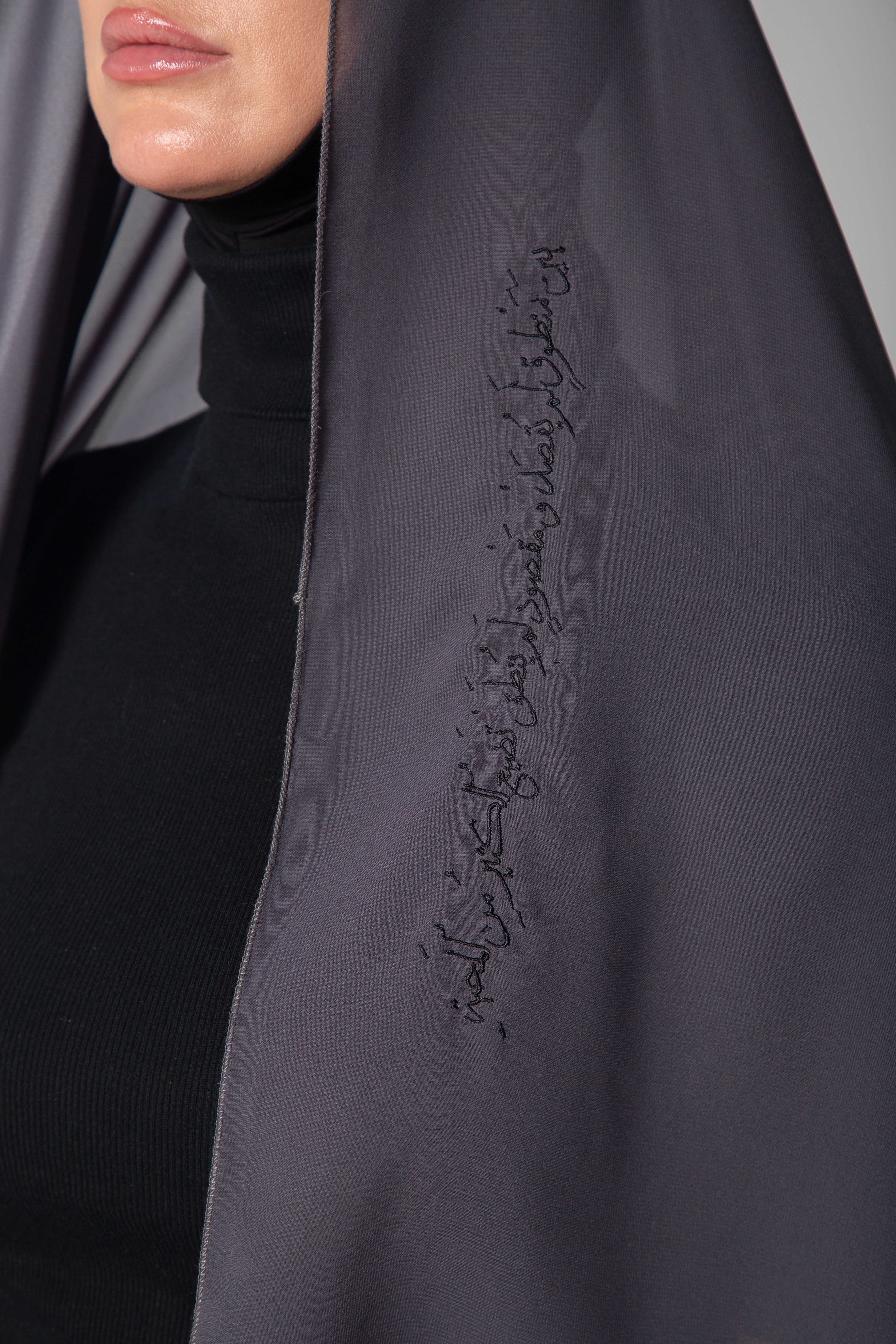 A woman wearing a light gray scarf with black embroidery KSA UAE Qatar