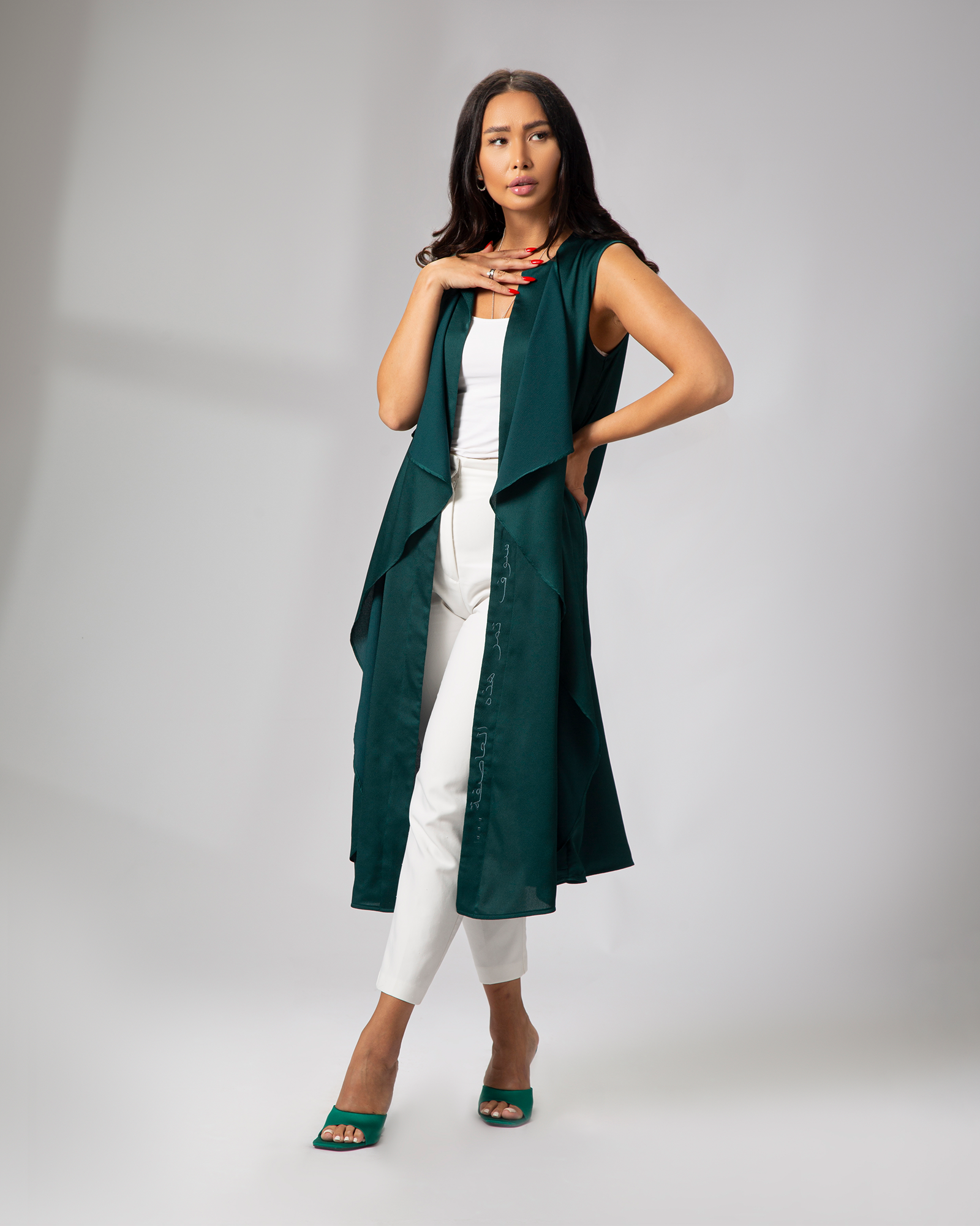 Model in sleeveless green cover-up with Arabic embroidery, styled over white outfit UAE, KSA, Qatar