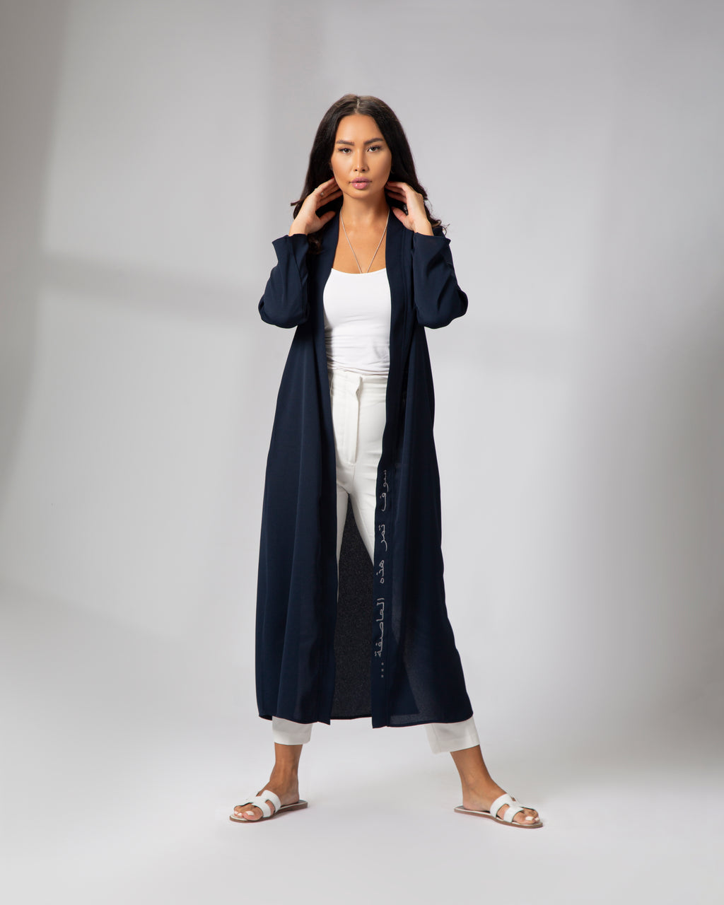 Full-length front view of a woman wearing the navy kimono, styled open with white outfit underneath KSA UAE Qatar