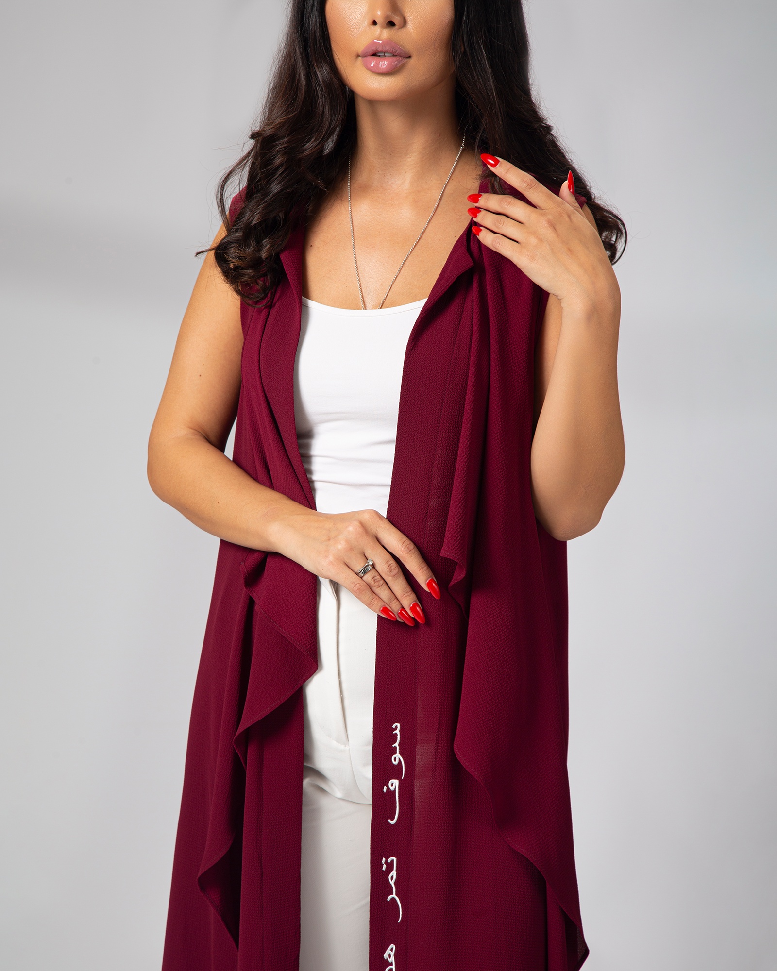 Model adjusting the front of Omni The Label burgundy cover up statement layering piece UAE Qatar KSA