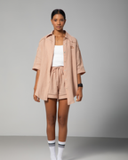 Woman wearing a nude linen co-ord set with short-sleeve shirt and drawstring shorts from Omni The Label, styled with a white top for a minimal summer look UAE KSA Qatar