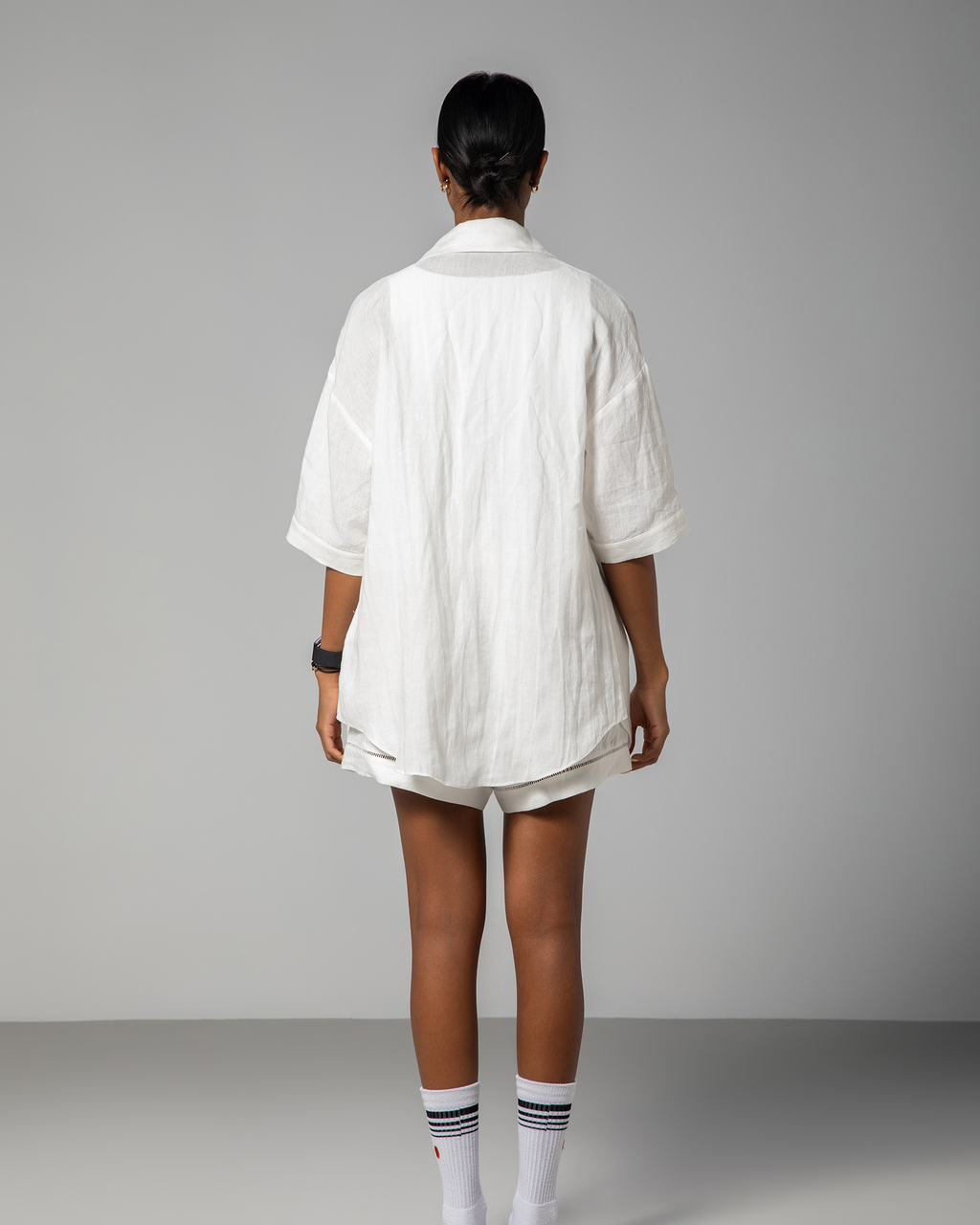 Back view of white linen shirt and shorts set from Omni The Label, showcasing loose tailoring and minimalist silhouette.UAE, KSA, Qatar