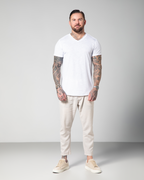 Male model wearing the Marbella V-neck T-shirt in white by Omni The Label, made from 100% slub jersey for breathable, lightweight comfort.UAE, KSA, Qatar
