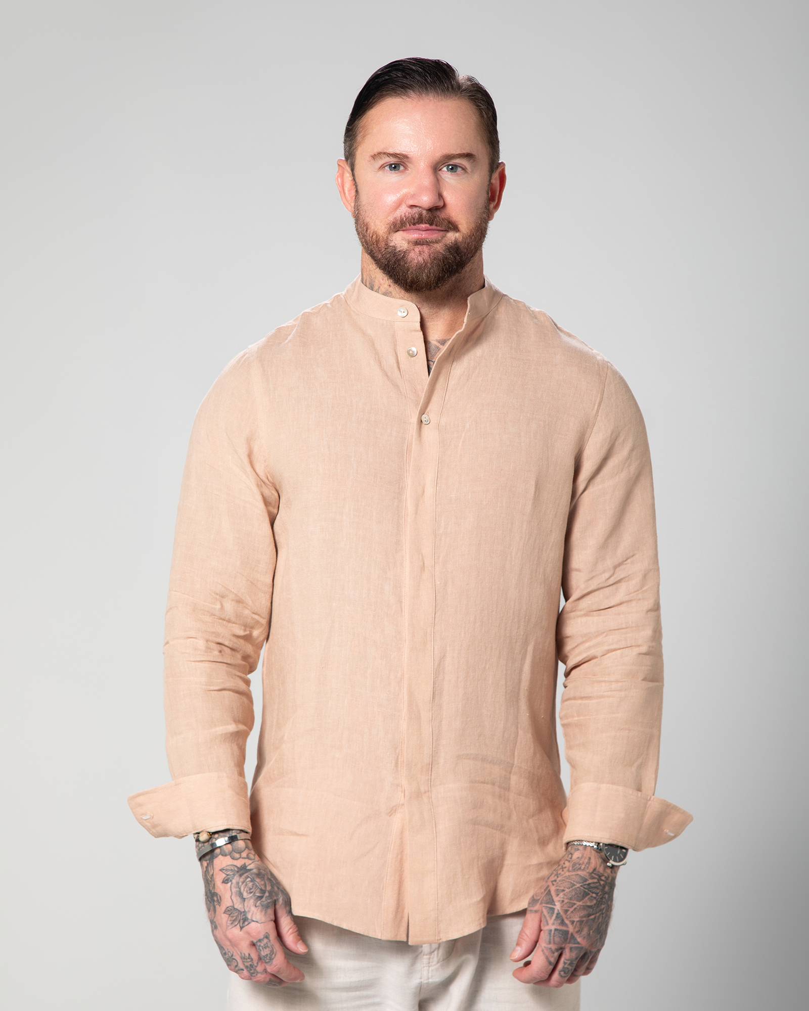 Model wearing the nude St. Tropez linen shirt from the front, showcasing its sleek, button-down design and relaxed fit Male model walking in the Marbella nude T-shirt by Omni The Label with Arabic embroidery reading this too shall pass shown in motion to highlight soft lightweight slub jersey fabric ideal for UAE KSA Qatar
