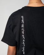 Close-up of white Arabic calligraphy print vertically aligned on the back of Omni The Label’s black T-shirt, delivering an inspiring message.