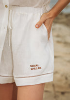 Relaxed-fit white linen shorts styled with hands in pockets, capturing ease of movement and breathable design.UAE, KSA, Qatar