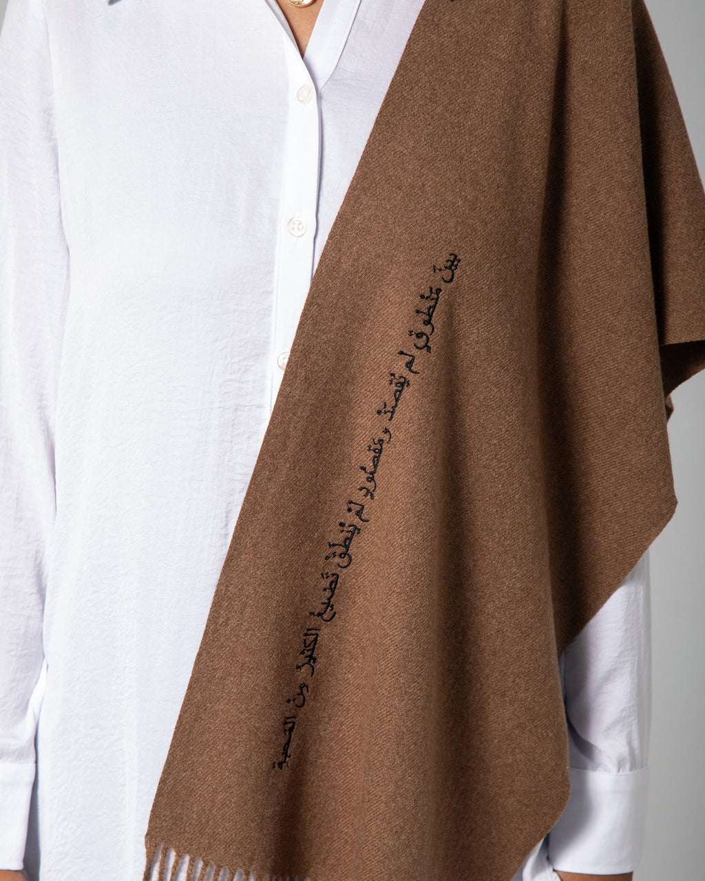 Close-up of Arabic calligraphy embroidery on brown scarf with soft woven texture – UAE, KSA, Qatar