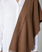 Close-up of Arabic calligraphy embroidery on brown scarf with soft woven texture – UAE, KSA, Qatar