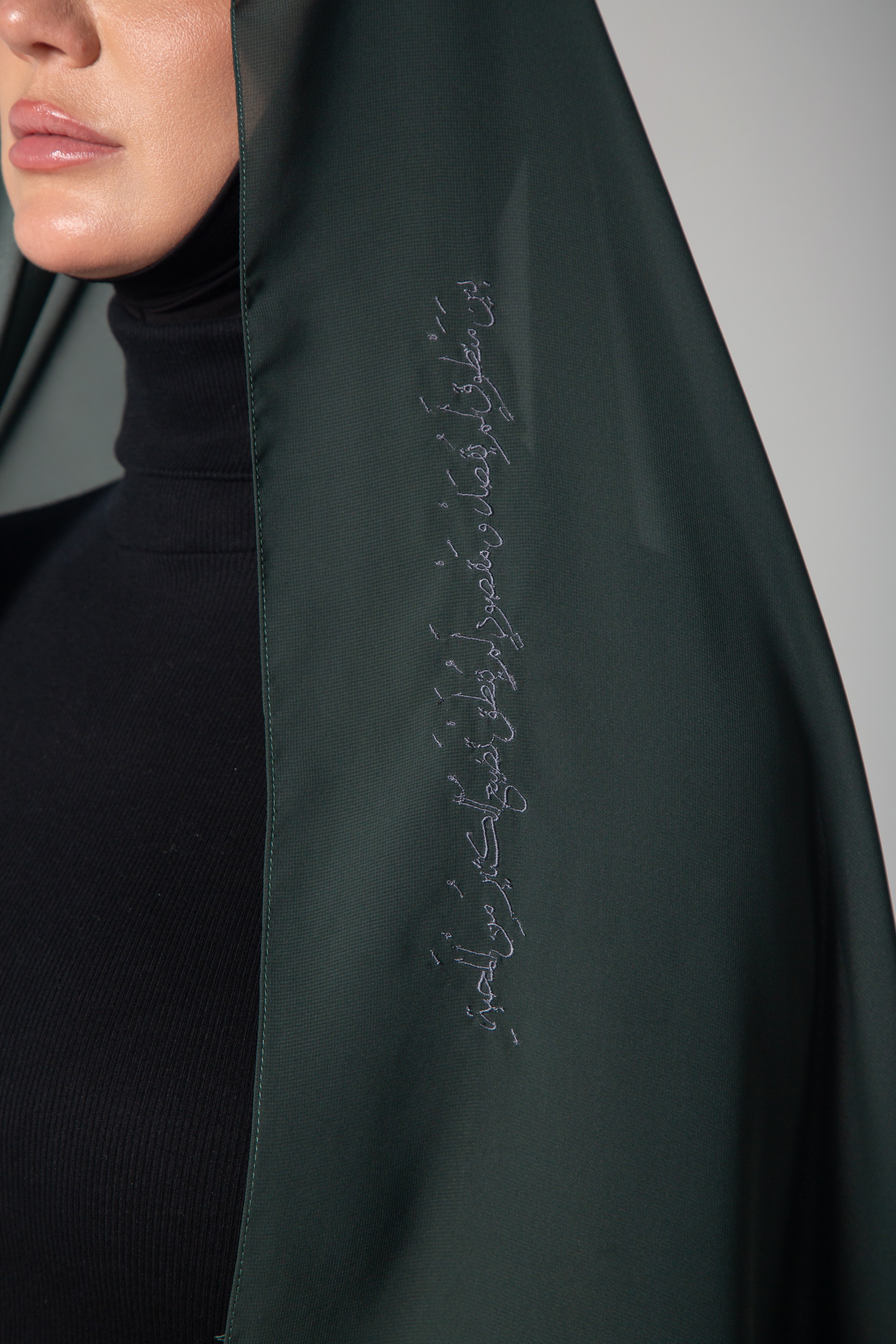 A woman wearing a dark green scarf with gray embroidery KSA UAE Qatar