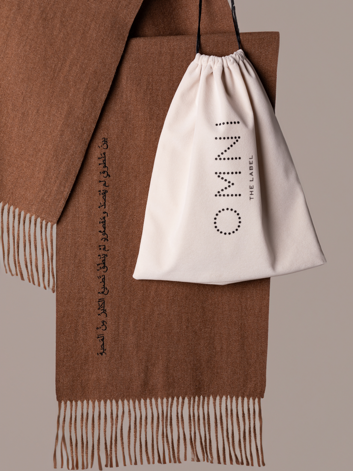 Brown scarf neatly folded with Omni The Label packaging and Arabic message visible – UAE, KSA, Qatar
