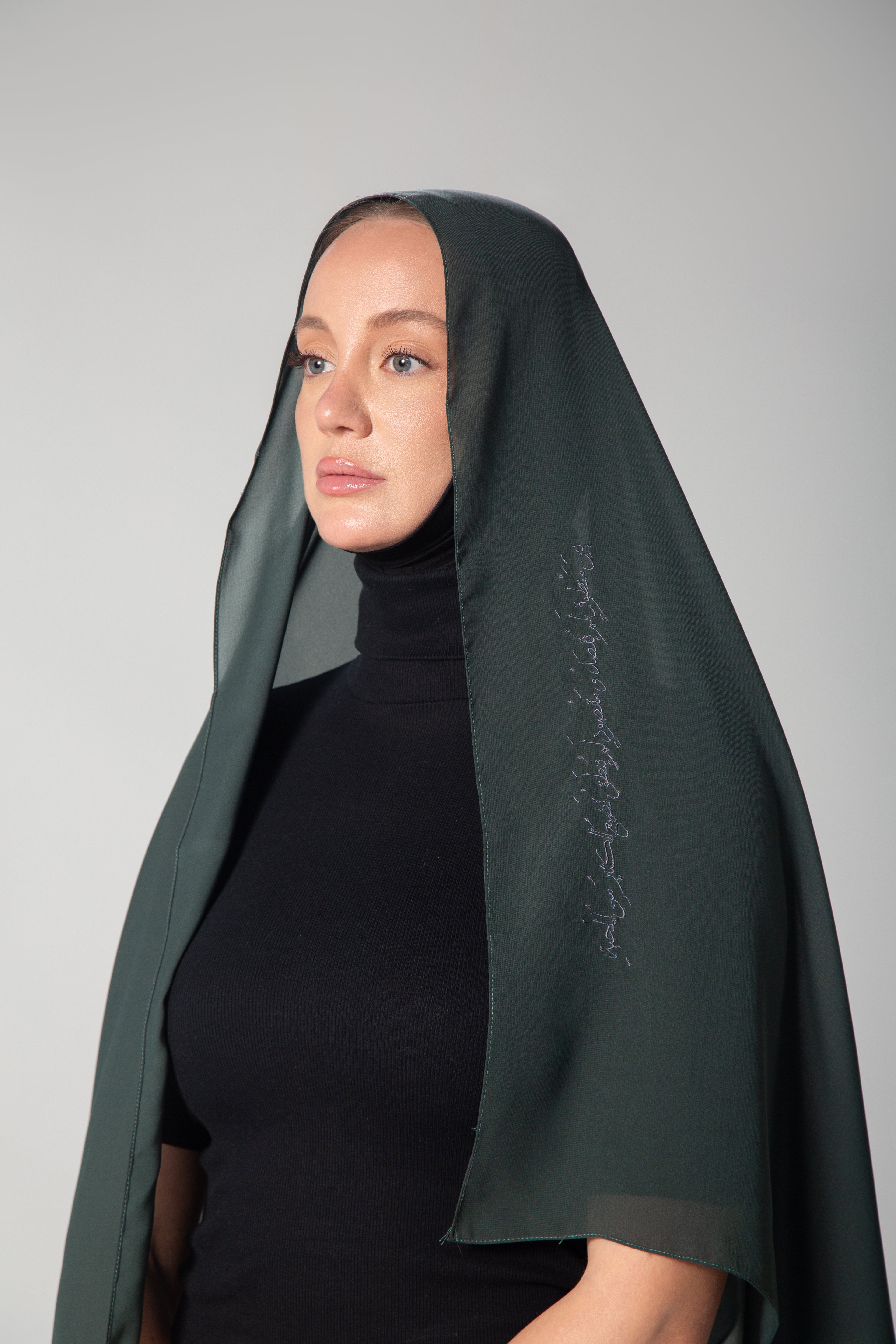 A woman wearing a dark green scarf with gray embroidery KSA UAE Qatar