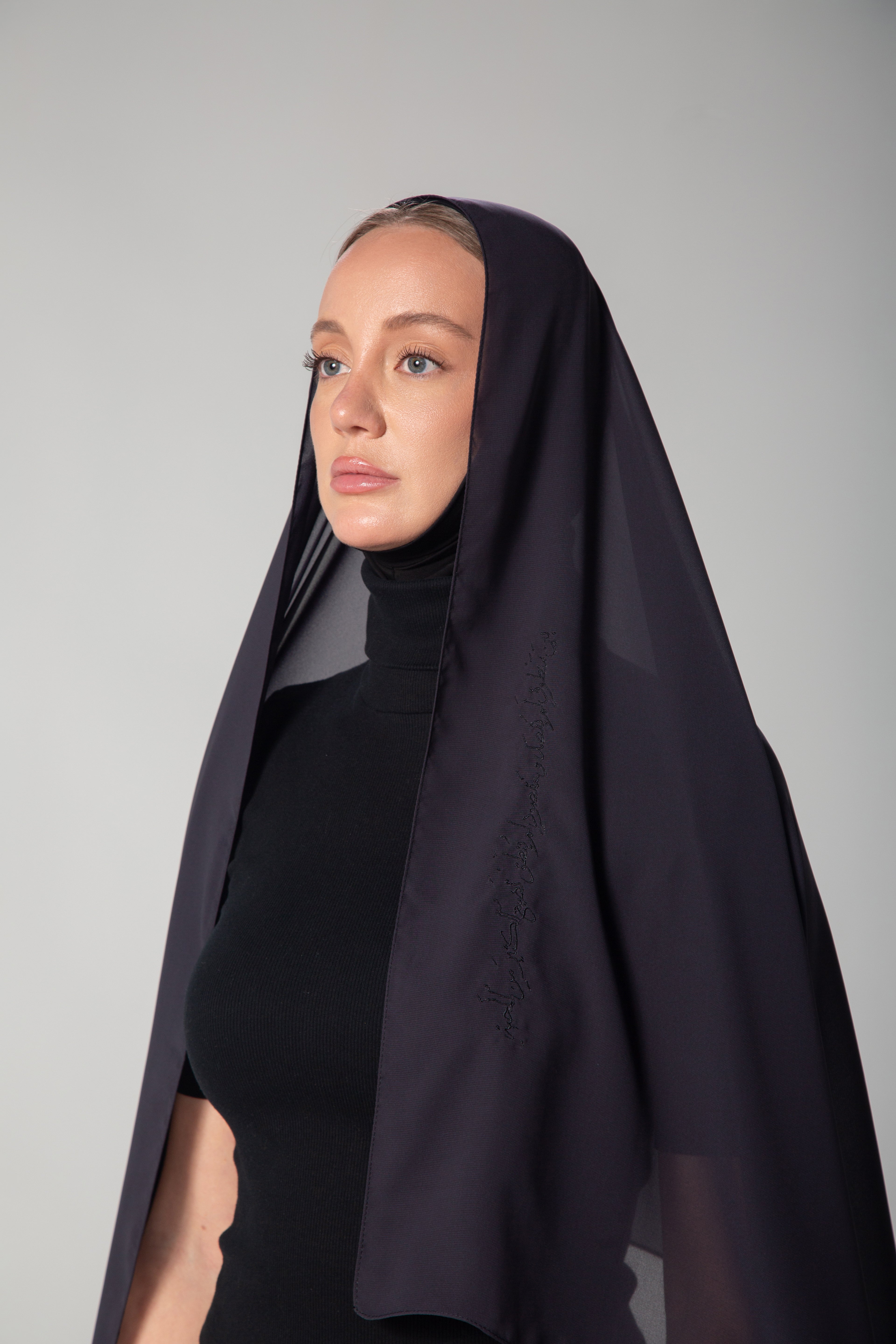 A woman wearing a dark gray chiffon scarf with black embroidery KSA UAE Qatar
