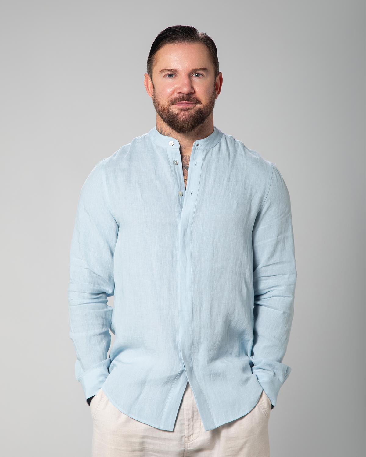 Model wearing light blue linen shirt from Omni The Label, partially buttoned, standing with relaxed posture KSA UAE Qatar