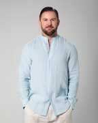Model wearing light blue linen shirt from Omni The Label, partially buttoned, standing with relaxed posture KSA UAE Qatar