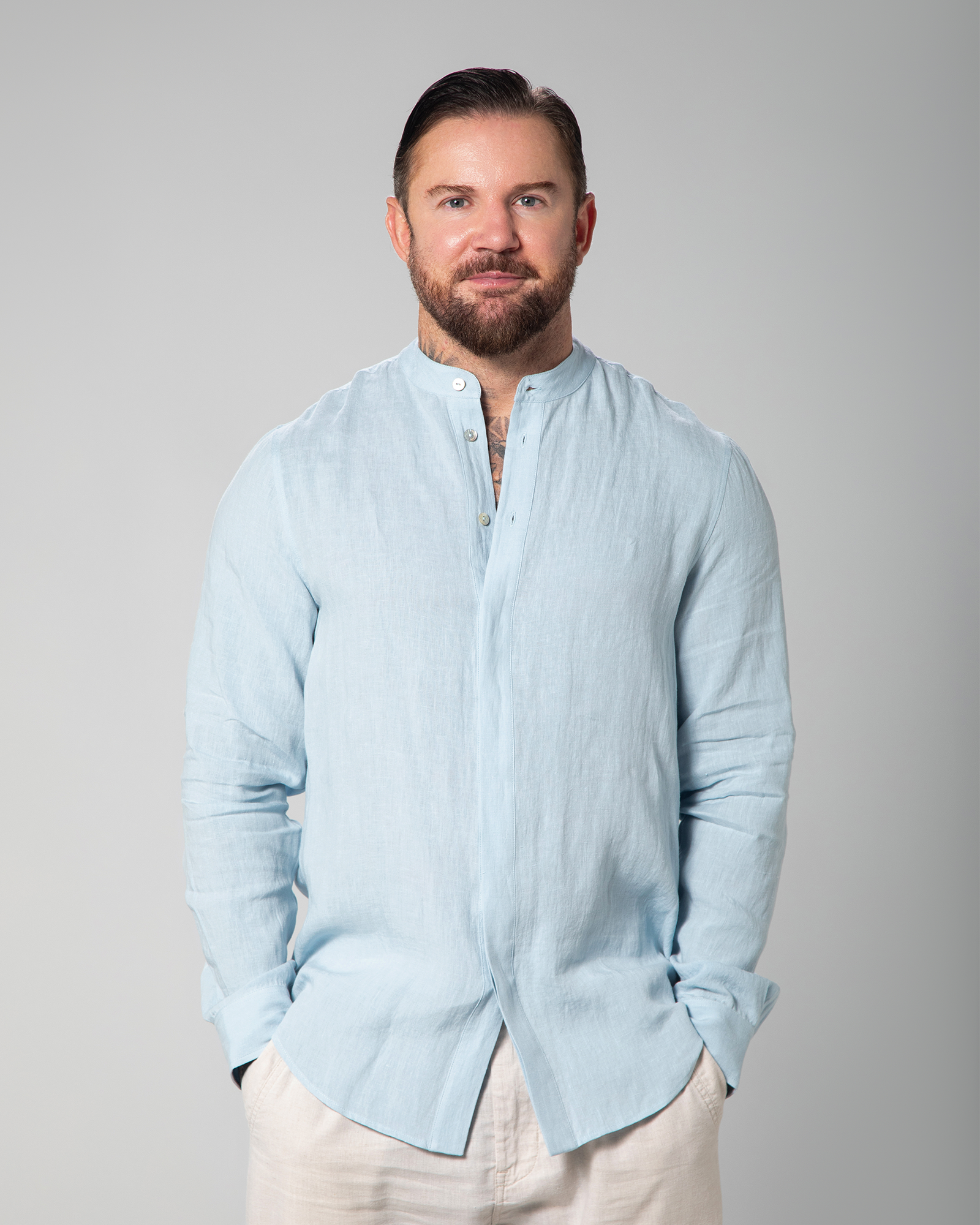 Model wearing light blue linen shirt from Omni The Label, partially buttoned, standing with relaxed posture KSA UAE Qatar