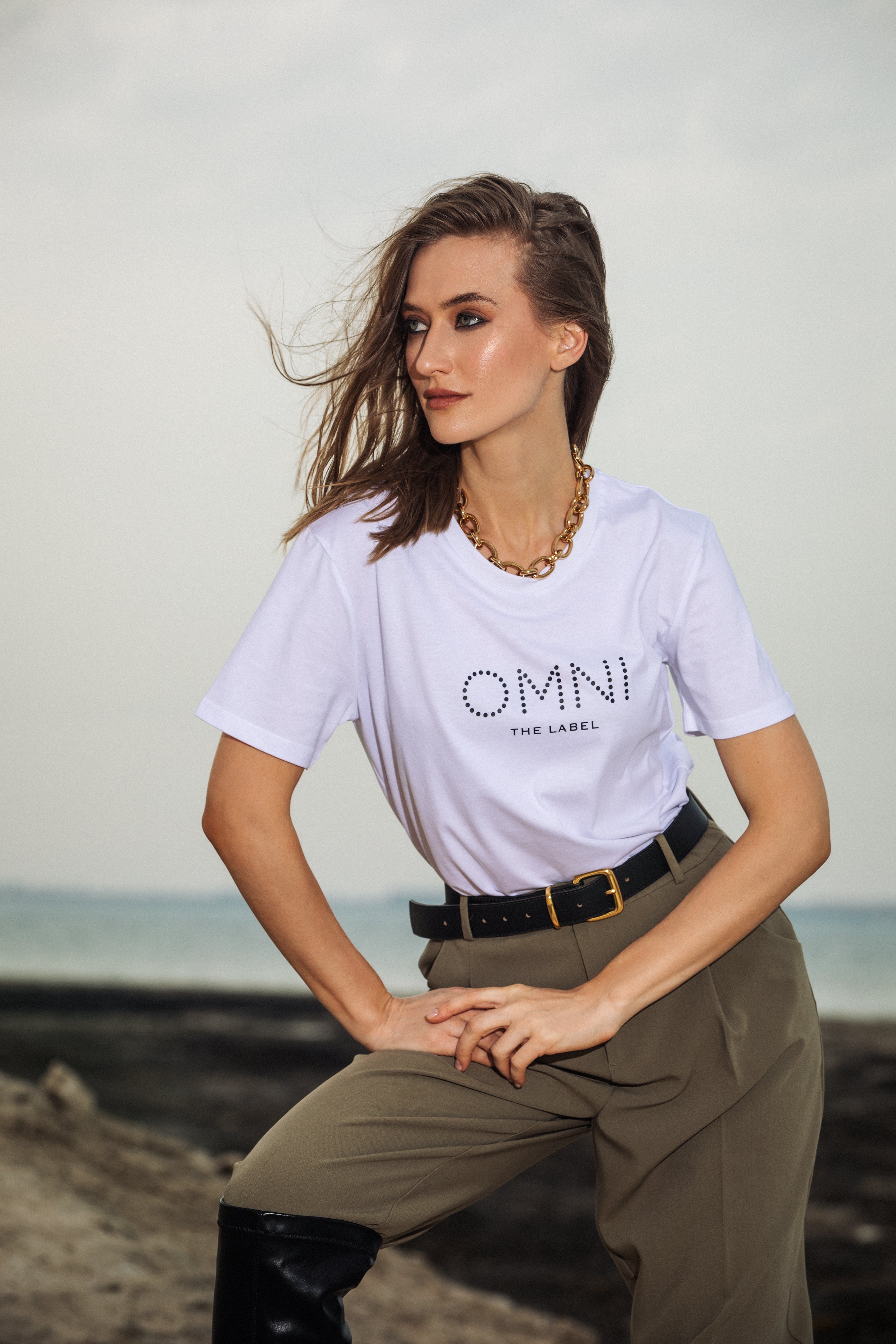 Front view of white T-shirt by Omni The Label featuring minimalist “OMNI” print—modern design Qatar, UAE, KSA
