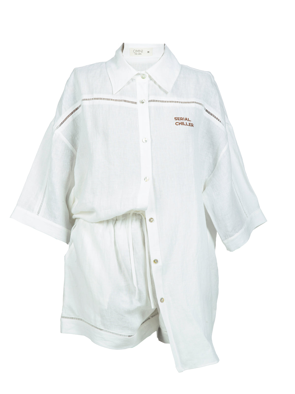 Close-up of Omni The Label’s white linen shirt featuring the “Serial Chiller” embroidery in fine script, highlighting the relaxed and playful summer aesthetic.UAE, KSA, Qatar