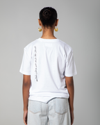 Woman wearing white fitted T-shirt with Arabic calligraphy print on the back, designed by Omni The Label. Modern streetwear  Qatar, UAE, KSA. Sustainable fashion meets culture and comfort.
