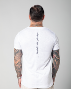 A man wearing a white Marbella V-neck T-shirt with Arabic embroidery on the backUAE, KSA, Qatar