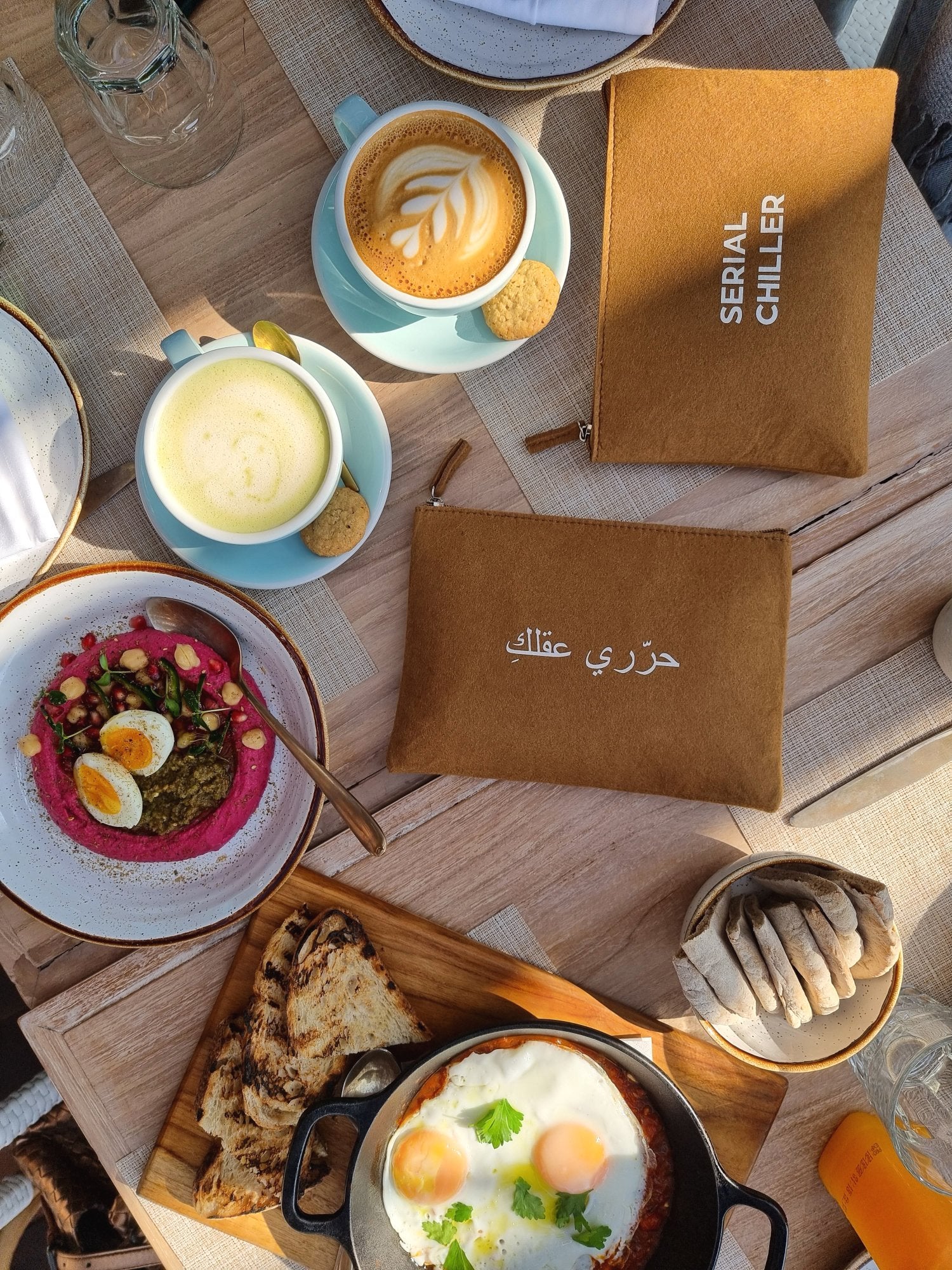 Minimalist brown fit zipper pouch with Arabic print free your mind, styled with breakfast setting — perfect for daily essentials.UAE, KSA, Qatar